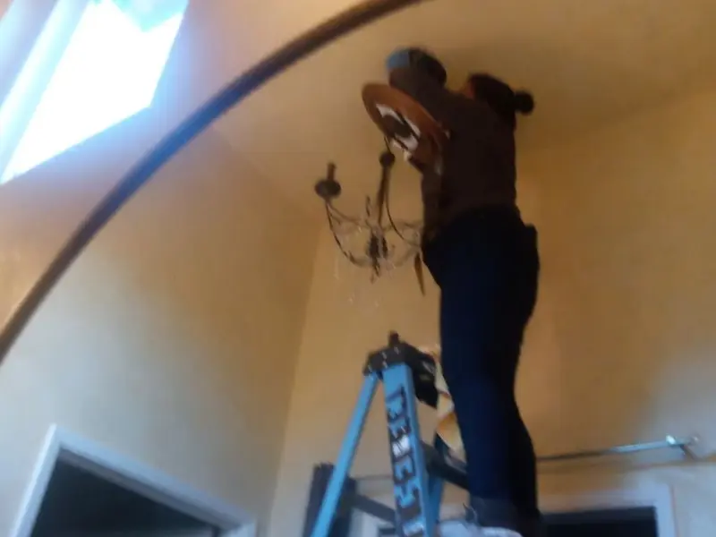 Electrician installing a chandelier in a Countryside residence